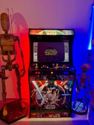 Arcade Titan avec piédestal Star Wars de Marc allumée, entre deux droïdes grandeur nature