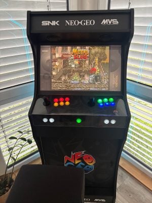 Arcade King XL con pedestal de Holger con vinilos Neo Geo, de frente, con Metal Slug en pantalla y los botones translúcidos iluminados