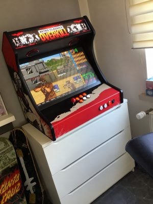 Bartop King XL de Timo aux vinyles personnalisés noir, rouge et blanc, allumé sur une commode, avec joystick Sanwa rouge et boutons chromés lumineux